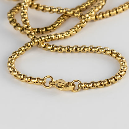 A close-up image displaying a fine gold chain with a detailed box link design, which catches light to create a subtle shimmer. The secure lobster claw clasp is also visible, indicating the functional and aesthetic care taken in the design of the jewelry. This piece reflects the elegant, minimalist style akin to DriftElement's innovative approach to watch design, incorporating automotive elements, as demonstrated by their unique wheel-inspired watches, from a creative startup based in Germany.